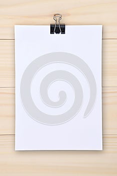 Black clip and white paper on wooden background