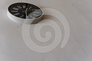 Black clock hanging on the white wall