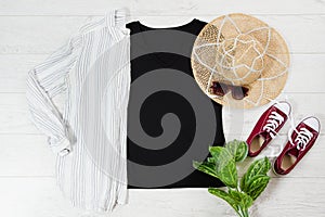 Black closeup t shirt mock up flat lay on white wooden background. Top view and copy space. Mockup t-shirt and summertime.