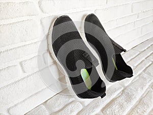 Black cloth sports sneakers on white brick background