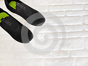 Black cloth sports sneakers on white brick background