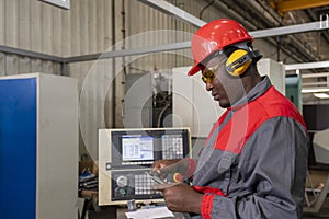 Black CNC Machine Operator In Protective Workwear Checking Measurements With Vernier Caliper