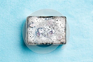 Black coal bar of soap in foam on blue background