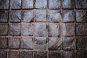 Black cobbled stone road with reflection of light texture background
