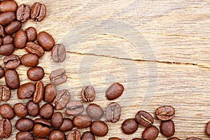 Black coffee beans seed scattered on brown matte wooden table, dark cofee espresso roasted grain flavour aroma cafe