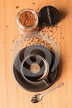 Black coffee in black cup and jar of coffee on the wooden table