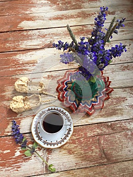 Black coffee and bouquet of wild flowers on a old brown wooden background