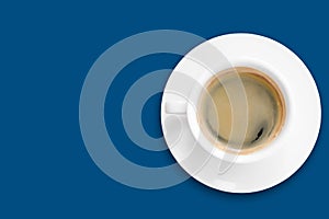 black coffee in a ceramic coffee cup above saucer in white color isolated on classic blue background