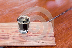 Black coffee in clear glass is placed on a wooden table.