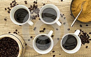 4 Black coffee cup with beans and sugar on wooden surface from a