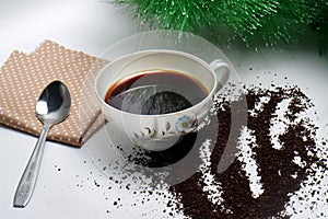 Black coffee in a cup with coarse coffee grounds and a brown cloth on white background and green plant
