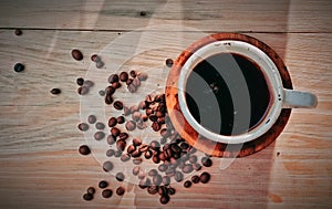 Black coffee in a cup with coffee beans On a brown wooden table before starting work activities