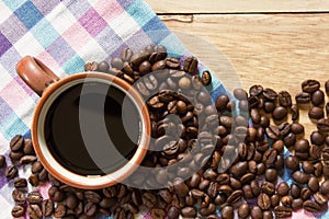 Black coffee in cup and coffee beans on the wooden table