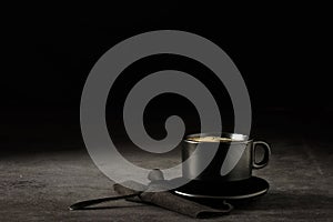 Black coffee cup with coffee on a dark background. With copy space for your text. Cup of coffee on a black background low key copy