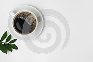 Black coffee in a cup with green leaves isolated on a white background