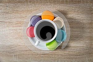 Black Coffee in a cup with macarons on white dish on wooden table background