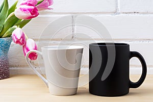 Black coffee cup and white latte mug mockup with magenta tulip