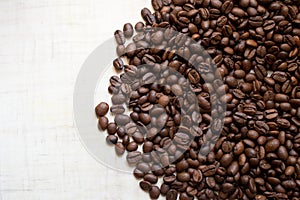 Black coffee grains lie on light wooden table, background image. place for text