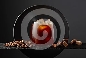Black coffee with ice on a black background