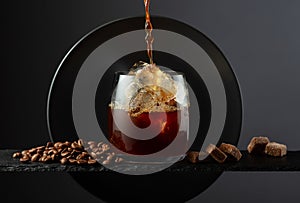 Black coffee with ice on a black background