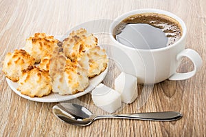 Black coffee, lumpy sugar, spoon and saucer with coconut cookies