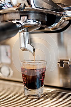 Black coffee in measuring cup put on coffee maker,coffee machine making espresso