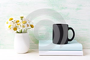 Black coffee mug mockup with white field chamomile bouquet in ha