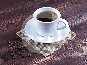 Black coffee in a mug with saucer coffee beans are scattered on