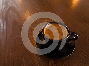 Black coffee mugs and spoon are placed on brown wood