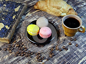 Black coffee and multicolored macarone on vintage background