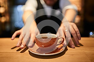 Black coffee in orange cup on brown wooden table background.