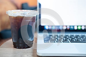 Black coffee in plastic cup with computer laptop