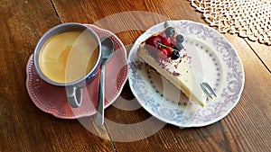 Black coffee and a slice of cake with fresh berries on a saucer are prepared for halftime coffee