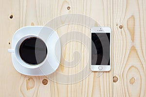 Black coffee and smartphone on wood background