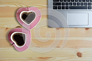 Black coffee in two pink cups heart shape and laptop computer on wooden floor, Copy space or empty space for text