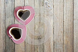 Black coffee in two pink cups heart shape on old wooden floor, Top view, copy space