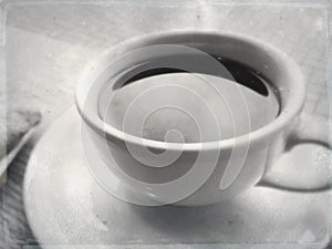 Black coffee in white ceramic cup and saucer in a cafe under natural light.