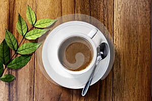 Black coffee in a white ceramic mug isolated on  wood table with leaves