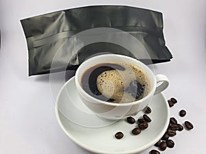 Black coffee in white cup, coffee beans on old wooden texture background.