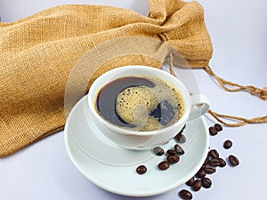 Black coffee in white cup, coffee beans on old wooden texture background.