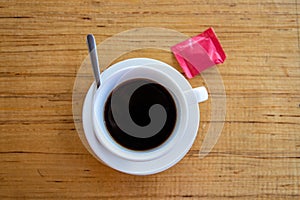 Black coffee in white cup on warm wooden table. Coffee drinking concept. Coffee cup and sugar top view photo