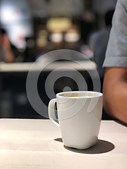 Black coffee in white cup on the wooden table with cafe light. Copy space