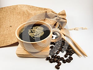Black coffee in wood cup, coffee beans on old wooden texture background.