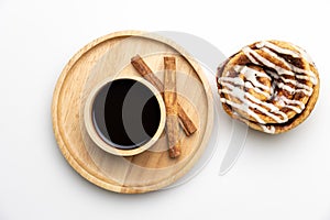 Black coffee in wooden cup with cinnamon stick and sweet cinnamon rolls on isolated background