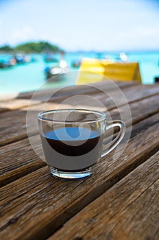 Black coffee on the wooden table, beachside, travel concept , nature light. Thailand