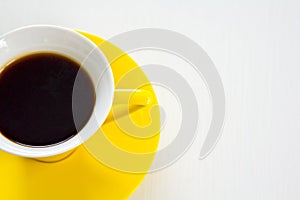 Black coffee in yellow cup and saucer