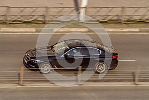 Black color BMW drive fast on city street. The car moves on the road with motion blur. Speeding in the city is not permissible