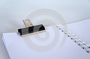 Black color bulldog clip clipping small white notebook