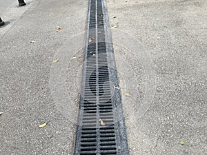 Black color epoxy painted floor drain channel gratings across asphalt road in residential area location for drainage purpose