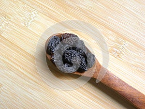 Black color raisin on spoon